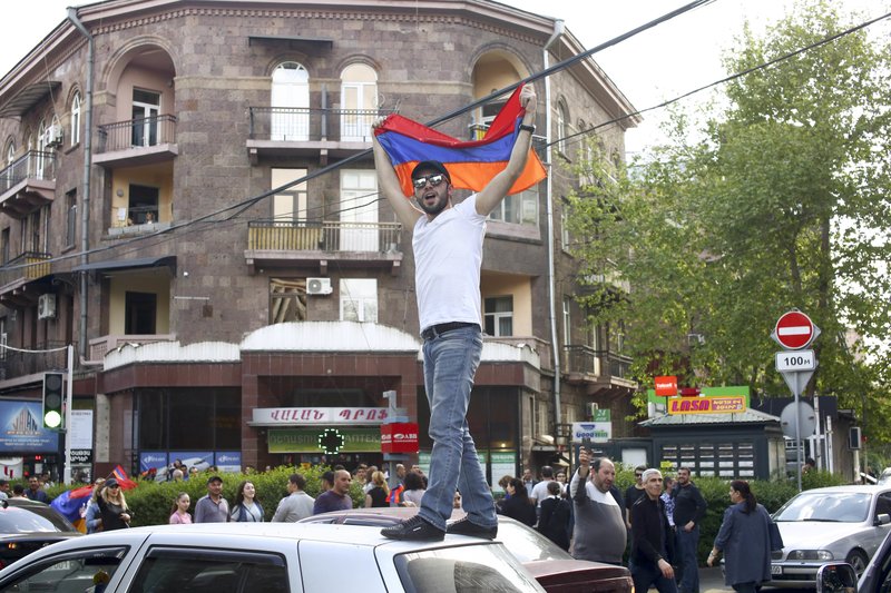 A man waves an Armenian national flag celebrating Armenian Prime Minister’s Serzh Sargsyan’s resignation in Republic Square in Yerevan, Armenia, Monday, April 23, 2018.