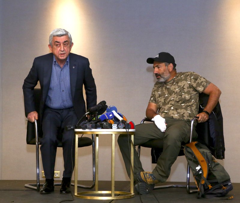 In this photo taken on Sunday, April 22, 2018, former Armenian President Serzh Sargsyan, left, leaves a meeting with protest leader Nikol Pashinian, right, in Yerevan, Armenia. Armenian Prime Minister Serzh Sargsyan has resigned, according to his website.