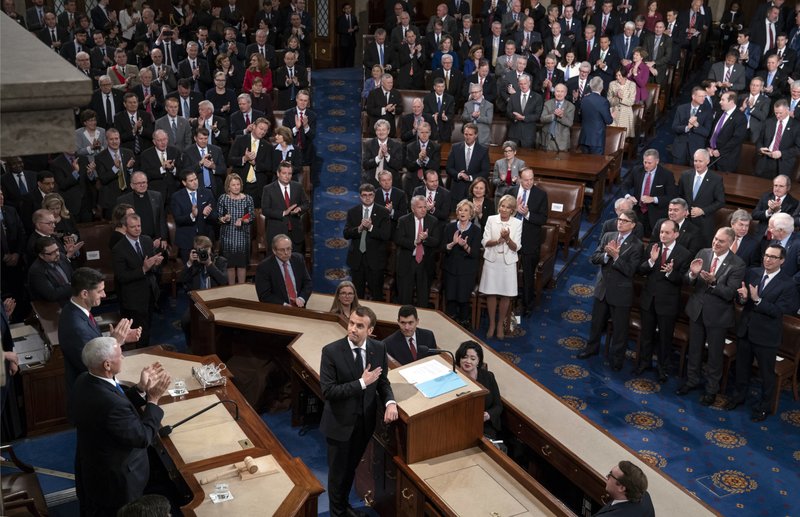 French President Emmanuel Macron touches his hand to his heart as he finishes his address to a joint meeting of Congress with Vice President Mike Pence and House Speaker Paul Ryan applauding at left, at the Capitol in Washington, Wednesday, April 25, 2018