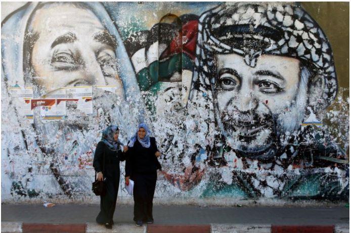 Palestinian students stand in front of a mural depicting late Hamas leader Ahmed Yassin and late Palestinian leader Yasser Arafat, in Gaza City October 12, 2017.