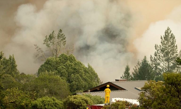 A firefighter watches smoke billowing from a blaze in Sonoma County, California