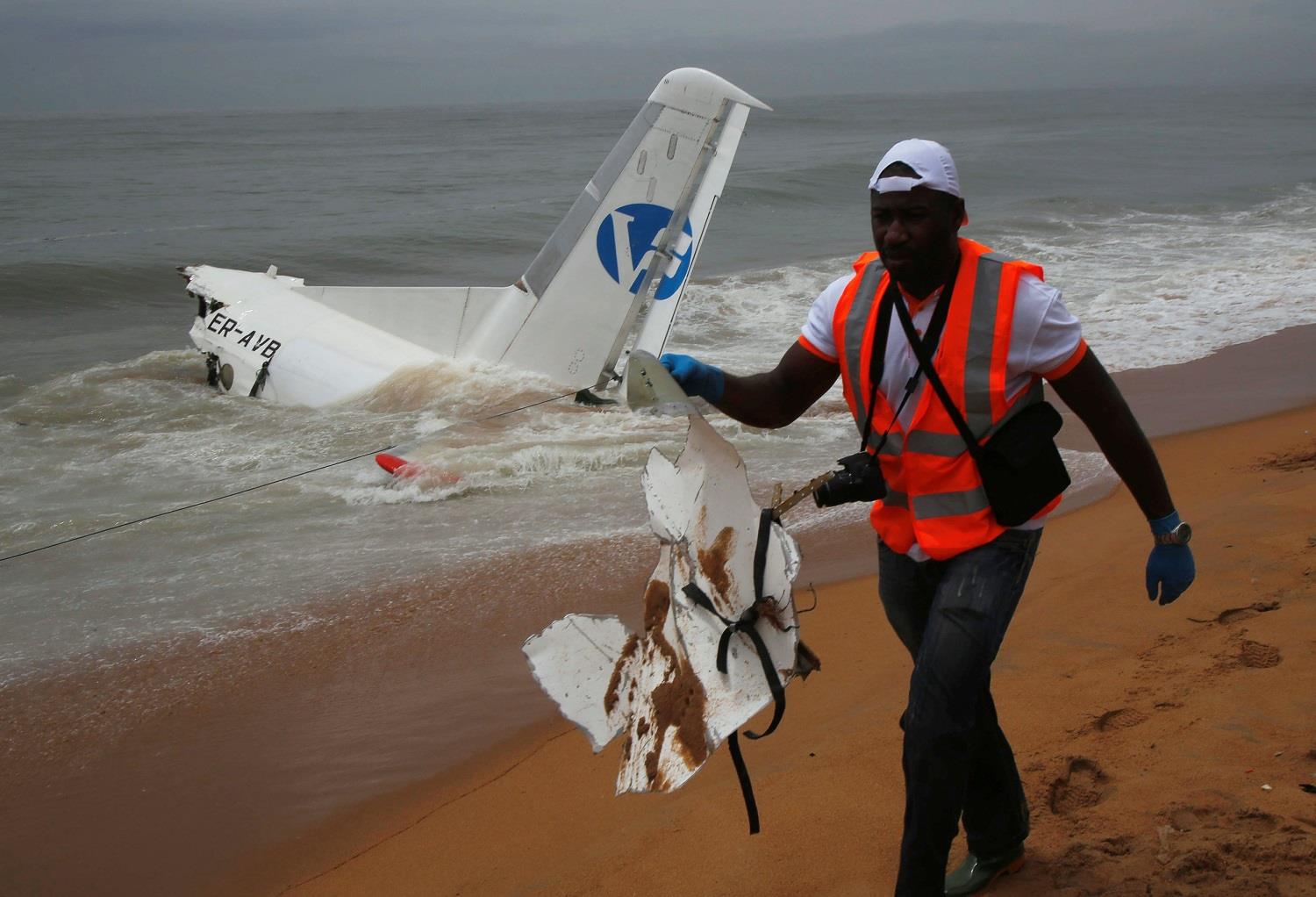 A rescuer carries a piece of a cargo plane after it crashed into the sea near the international airport in Ivory Coast’s main city, Abidjan