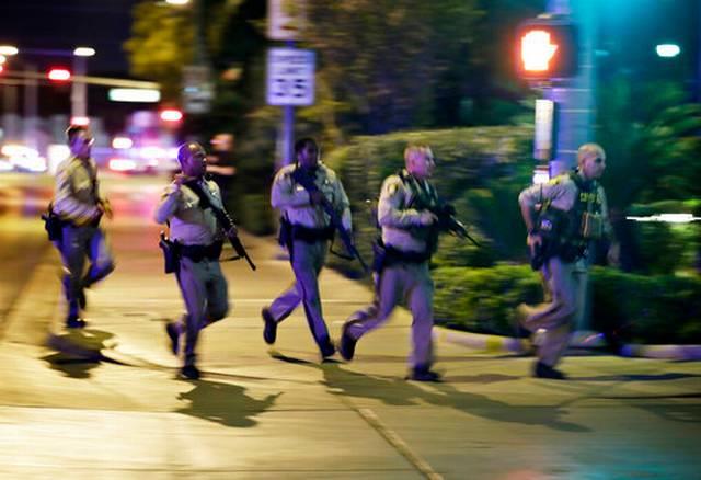 Police run to cover at the scene of a shooting near the Mandalay Bay