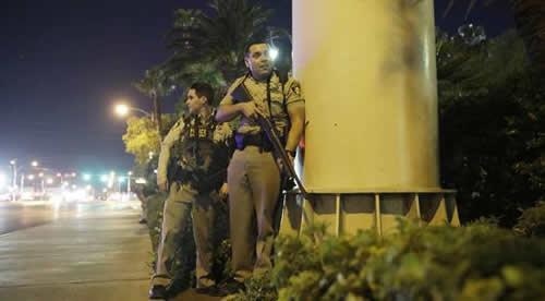 Police officers take cover near the scene of a shooting on the Las Vegas Strip