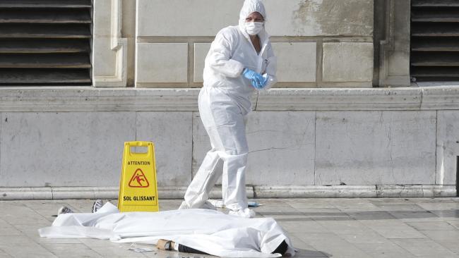  Investigative police officers work by a body under a white sheet outside Marseille's main train station