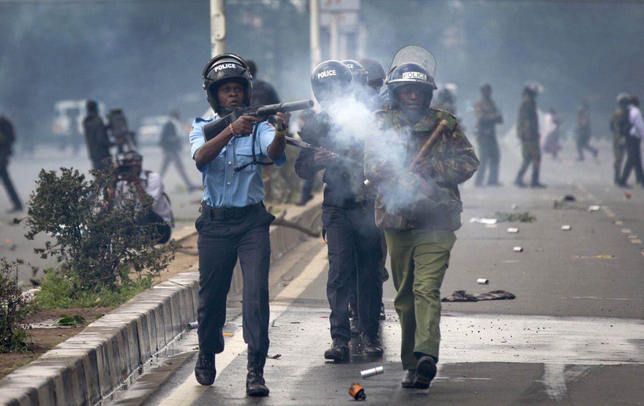 Riot police fire tear gas toward demonstrators as they flee during a protest in downtown Nairobi