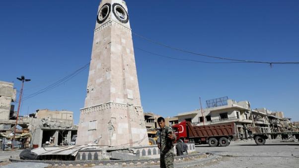 A fighter of Syrian Democratic Forces takes a selfie at a clock tower in Raqqa, Syria October 18, 2017.