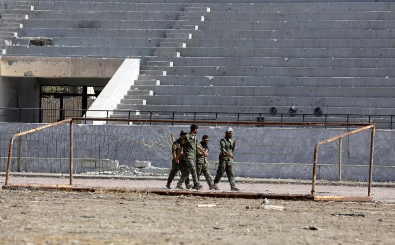  Fighters of Syrian Democratic Forces walk at the stadium in Raqqa, Syria October 18, 2017