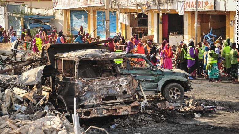 People gather near burned vehicles a day after a truck bomb exploded in the center of Mogadishu on October 15