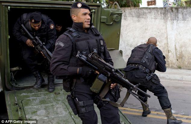 Police officers jump out of an armoured vehicle during 'peace' operations in the city