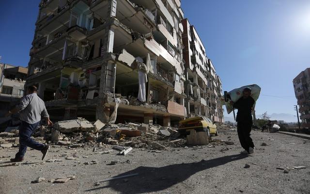 People walk past a damaged building following an earthquake in Sarpol-e Zahab county in Kermanshah, Iran Nov 13, 2017.