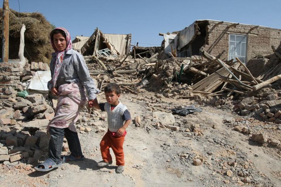 Iranian residents walk among the rubble of destroyed houses in a village after the quakes.
