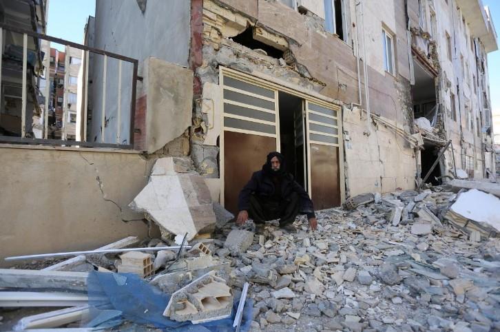 A man sits outside a damaged building following an earthquake in Sarpol-e Zahab county in Kermanshah, Iran