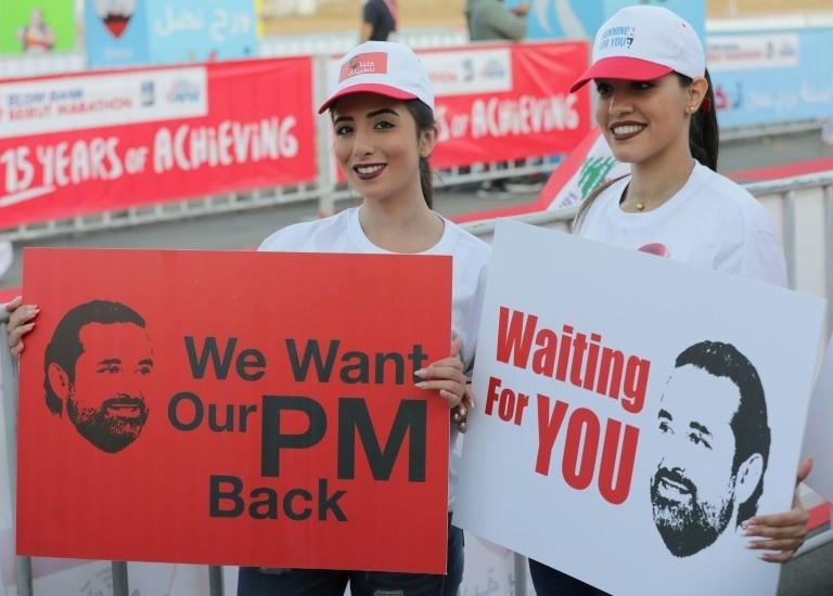Supporters Saad Hariri hold placards demanding his return from Saudi Arabia on the starting line of Beirut's annual marathon