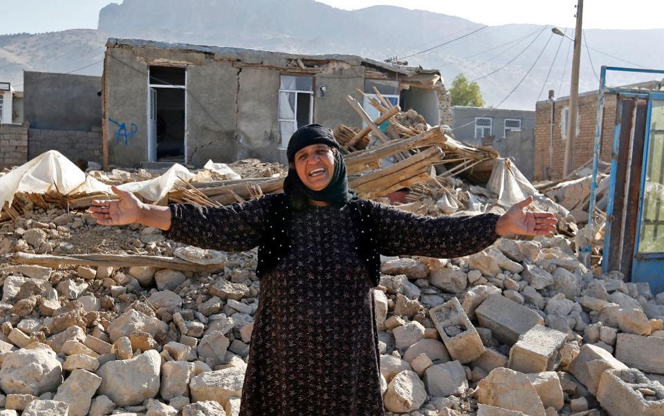 A picture taken on November 15, 2017 shows an Iranian woman gesturing next to the rubble of her home in Kouik village near to Sarpol-e Zahab, two days after a 7.3-magnitude earthquake struck Iran's western Kermanshah