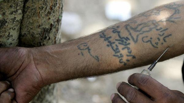 An Iranian drug addict injects himself with heroin in a park in Tehran