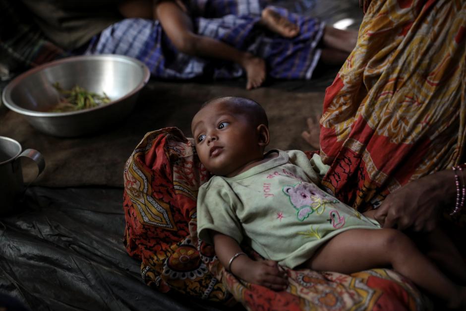 A Rohingya Hindu refugee woman holds her child inside their temporary shelter at the Kutupalong Hindu refugee camp near Cox's Bazar, Bangladesh December 17, 2017