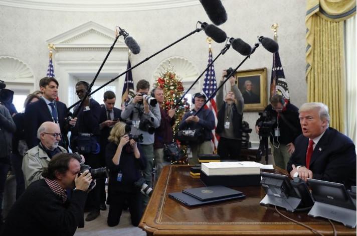 U.S. President Donald Trump sits at his desk while signing the $1.5 trillion tax overhaul plan in the Oval Office of the White House in Washington, U.S., December 22, 2017