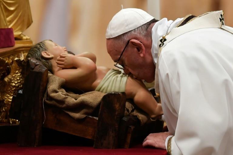 Pope Francis kisses a figurine of baby Jesus during a mass on Christmas eve