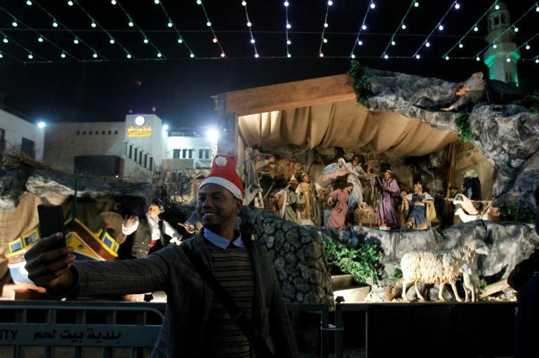 A man takes a selfie at the Manger Square outside the Church of the Nativity during Christmas Eve celebrations Bethlehem