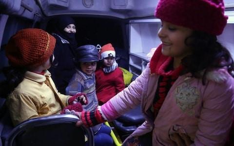 Syrian children sit in an ambulance during an evacuation operation by the International Committee of the Red Cross in Douma in the eastern Ghouta region on the outskirts of the capital Damascus late on December 26 