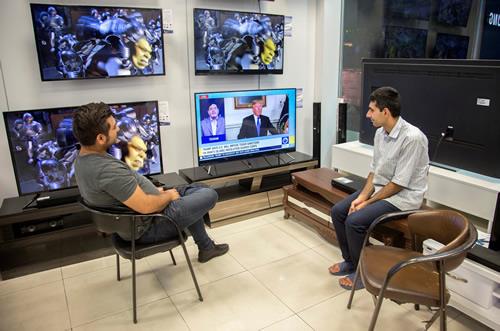 Men watch a television broadcast of US President Donald Trump’s speech, in Tehran on October 13, 2017.