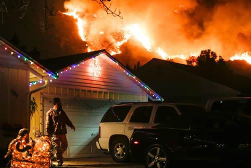 A man prepares to evacuate his home as a wildfire burns along a hillside near homes in Santa Paula, California