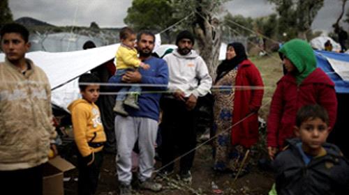 Syrian refugee Bashar Wakaa (3rd L) and his family stand in front of their tents at a makeshift camp for refugees and migrants next to the Moria camp on the island of Lesbos, Greece, November 30, 2017