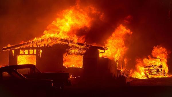 A car and house near Oroville, Calif., are engulfed in flames by the Wall fire