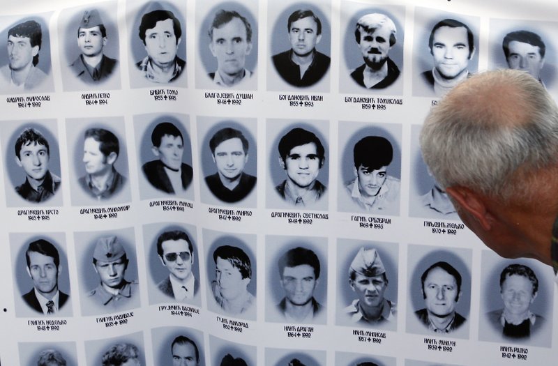 A man looks at a banner with pictures of Serbs killed by Bosnian forces during the 1992-95 Bosnian war