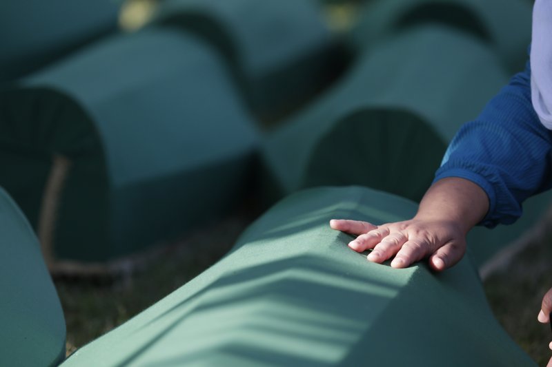 A Bosnian Muslim woman touches the coffin of her relative during a funeral ceremony for the 71 victims at the memorial center of Potocari near Srebrenica, north east of Sarajevo, Bosnia, Tuesday, July 11, 2017