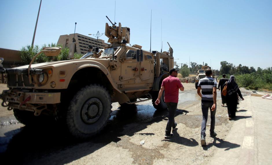  Iraqis pass American vehicles as they walk towards the floating bridge between east and west of Mosul, Iraq, July 21,2017.