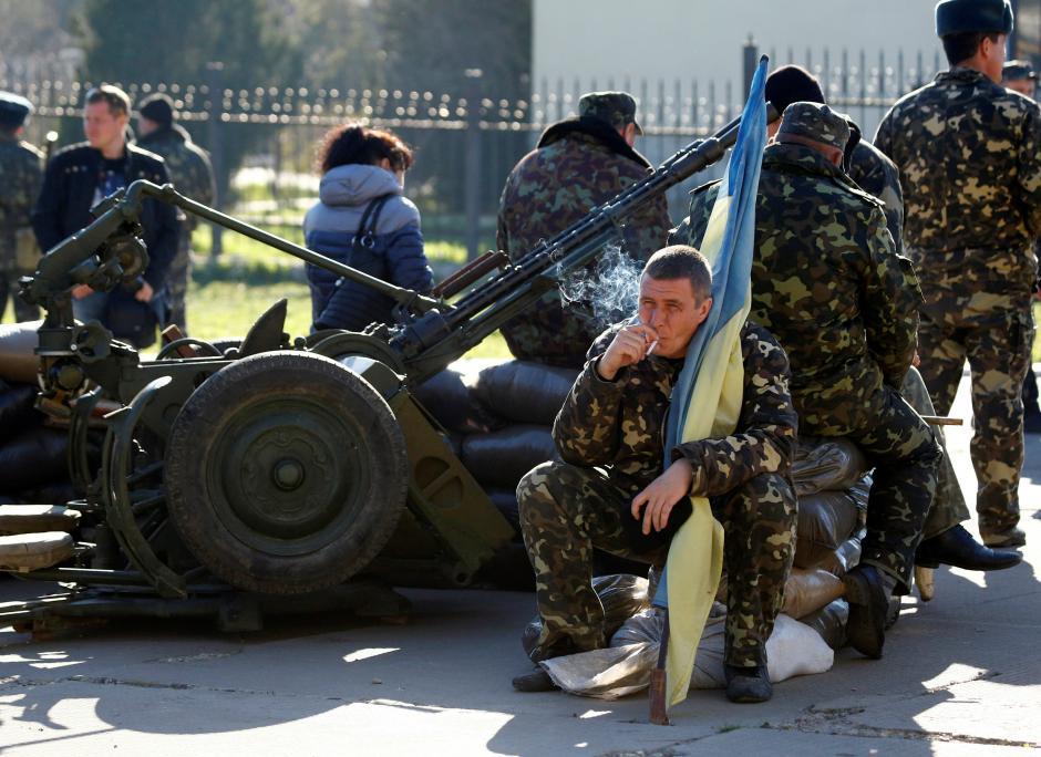  A Ukrainian serviceman holds a flag of Ukraine and smokes at a military base in the Crimean town of Belbek, near Sevastopol 