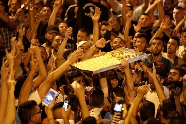 Palestinians celebrate by giving away sweets outside Jerusalem's Al-Aqsa mosque compound on July 27, 2017, after Israeli police removed the last new security barriers from the entrances 