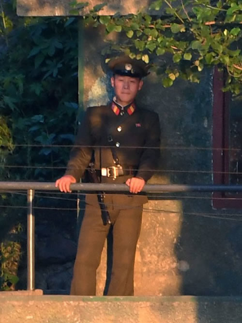 In this Tuesday, July 4, 2017 photo, a North Korean soldier guards in border town of Simuiju, North Korea, as he is seen from Dandong, northeastern Liaoning province of China