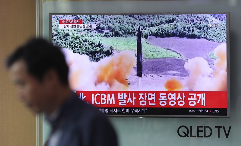 A man walks by a TV screen showing a local news program reporting about North Korea’s missile firing 