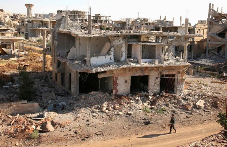  A rebel fighter walks past damaged buildings in a rebel-held part