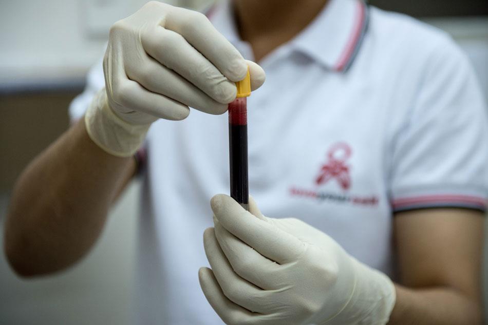 This picture taken on December 7, 2016 shows a nurse holding a vial containing blood from an individual that will be sent for HIV testing at the ...