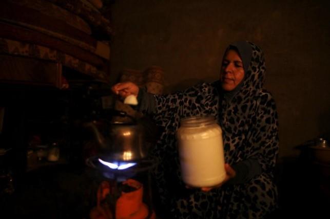 A Palestinian woman makes tea as she uses candle light during power cut in the kitchen of her house in Khan Younis in the southern Gaza Strip July 3, 2017.