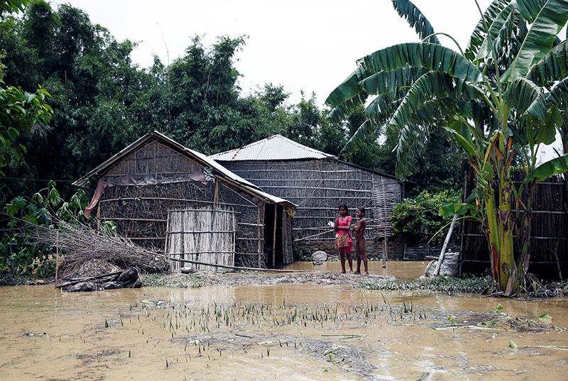Flood victims stands near a house at the flood affected area in Saptari District, Nepal August 14, 2017