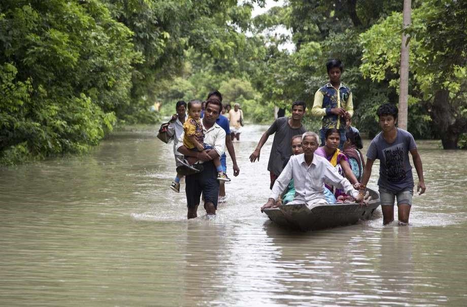 Commuters wade through flood waters on a road in Murkata village east of Gauhati