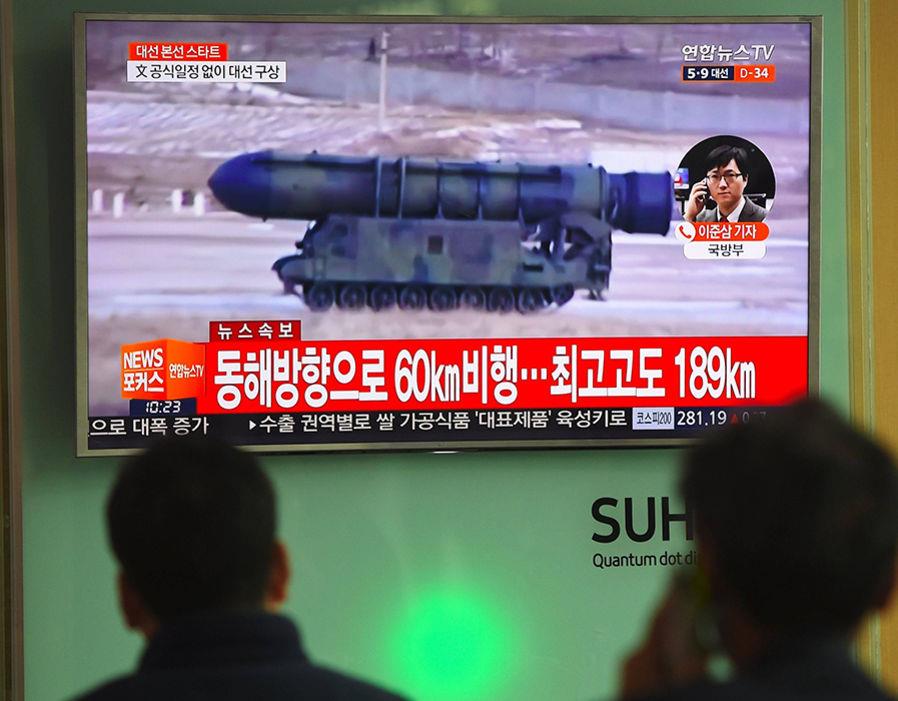 People watch a television news showing file footage of a North Korean missile launch