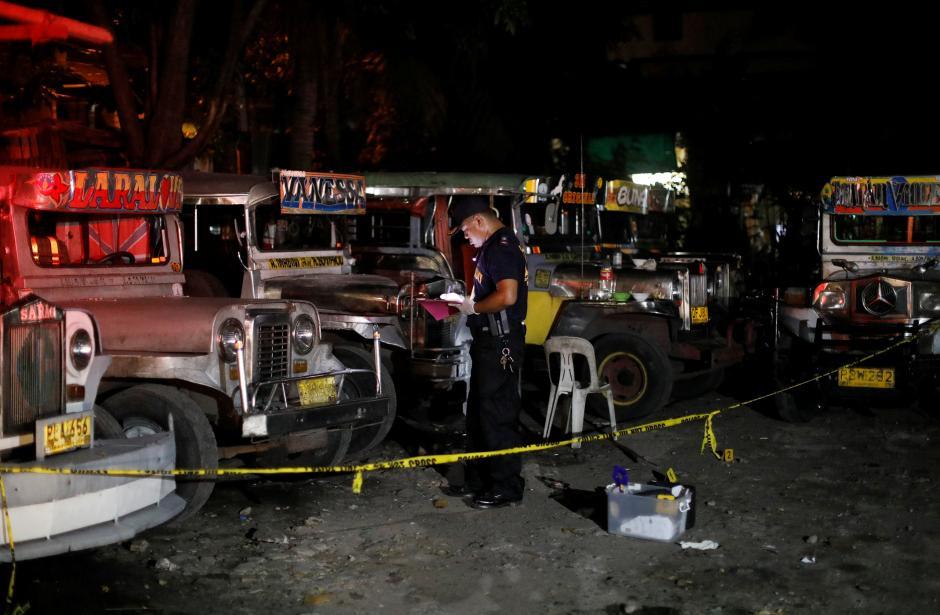 member of Philippine National Police Scene of the Crime operative examines a crime scene, where police said, a man was killed during anti-drug operations