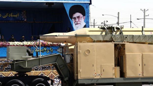 A military lorry carries a Qadr medium-range missile past portraits of Iran's Supreme Leader