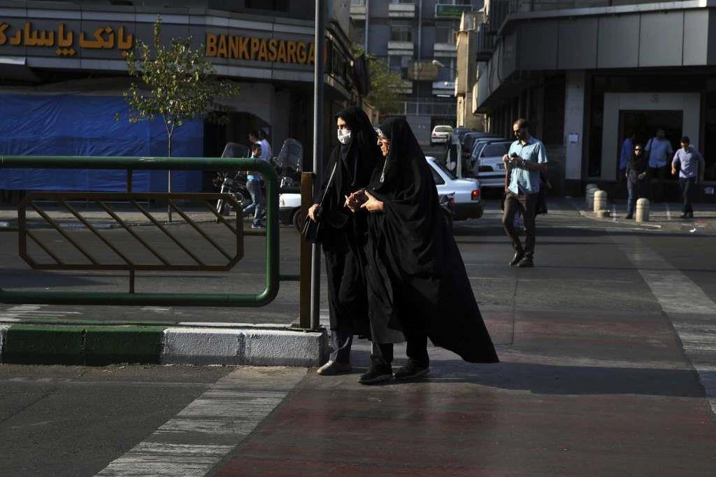 Two Iranian women cross a street while wearing the chador, a head-to-toe garment, in downtown Tehran, Iran.