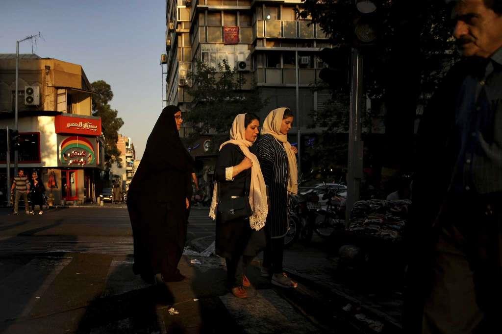 Iranian women cross a street while one of them wears the 'chador' in downtown Tehran, Iran.