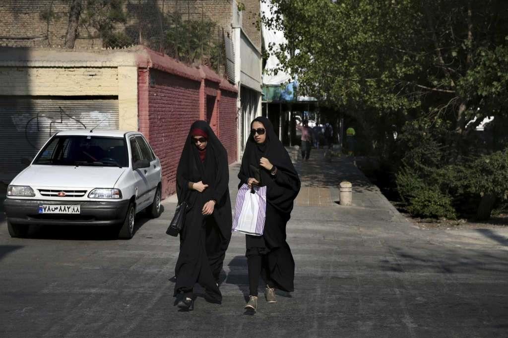 two Iranian women cross a street while wearing the 'chador,' a head-to-toe garment, in downtown Tehran, Iran.