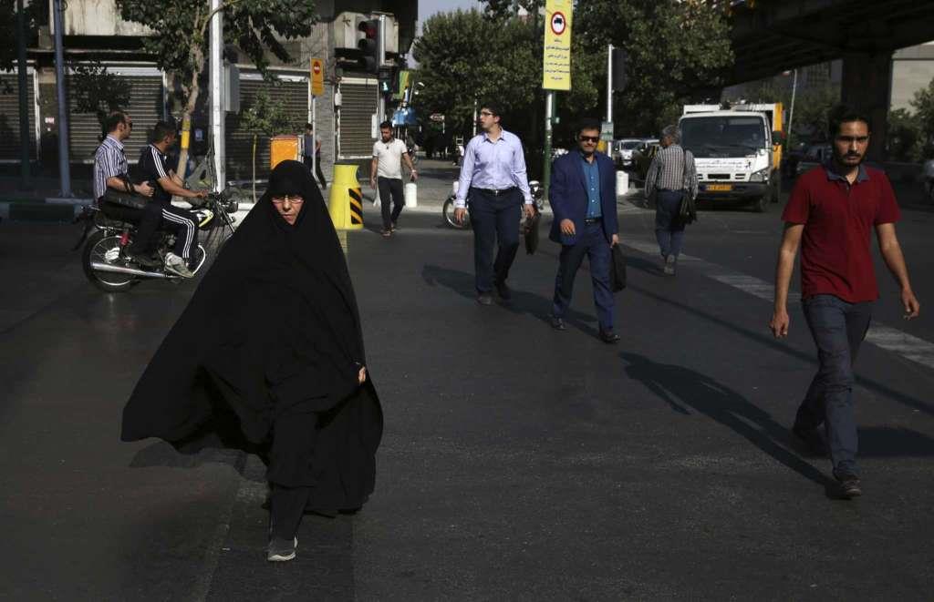 A woman crosses a street while wearing the chador in downtown Tehran