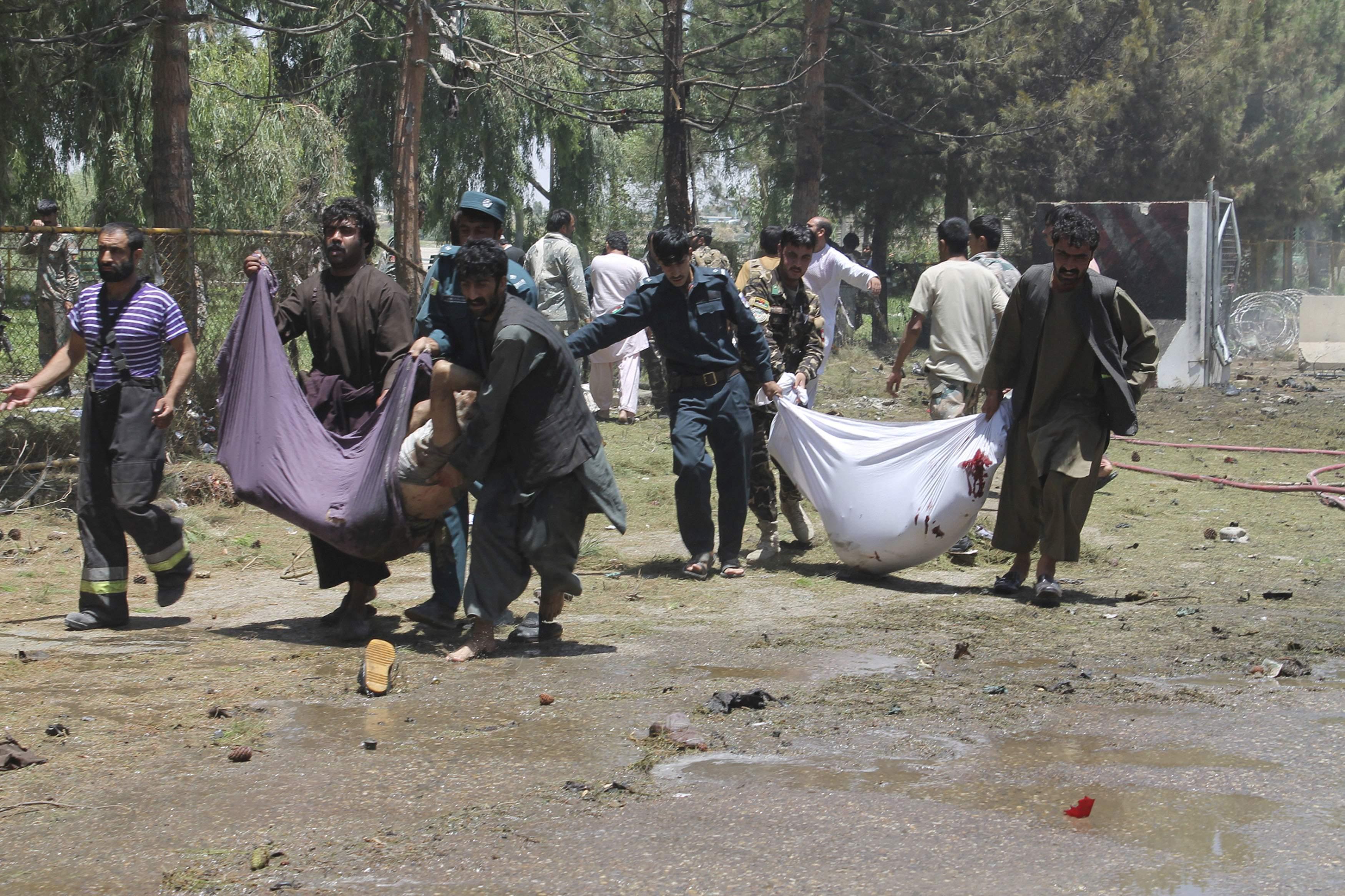 Afghans carry the bodies of men at after a suicide car bombing in Helmand province southern of Kabul, Afghanistan