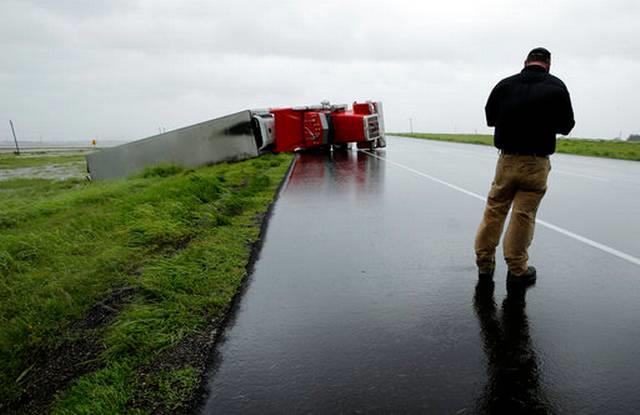  A passing motorist stops to look at a flipped truck in the aftermath of Hurricane Harvey